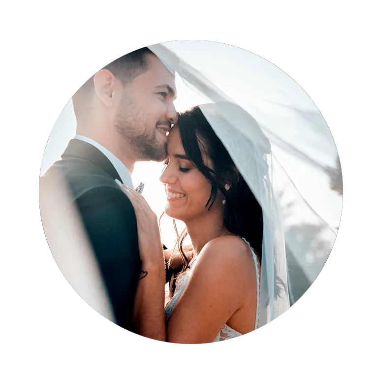 Mariée souriante sous son voile dans les bras de son époux