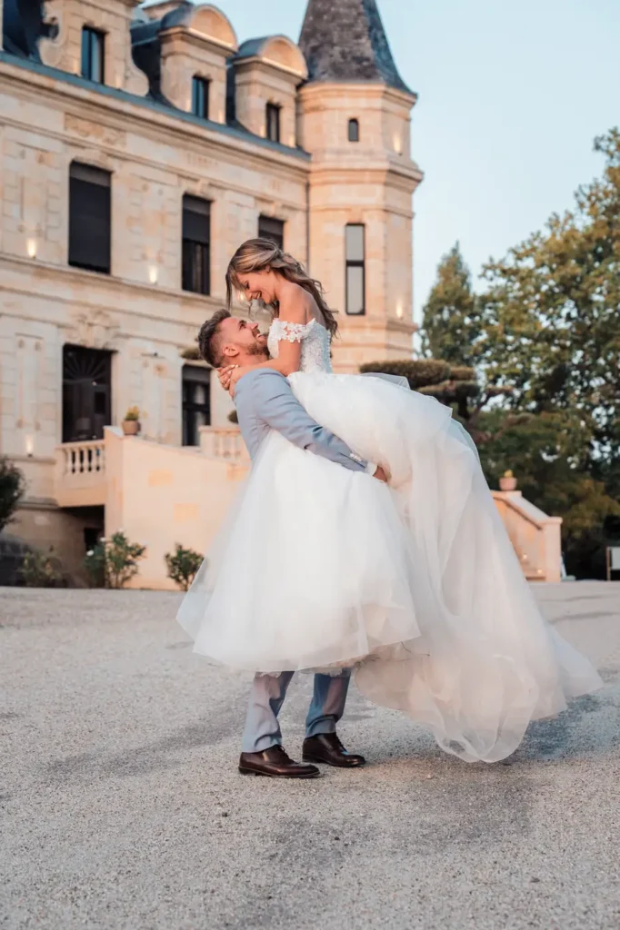 Marié portant la mariée devant le château