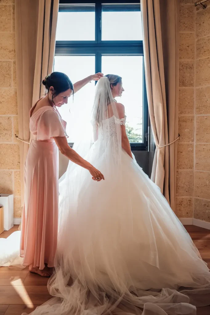 Mariée devant une grande fenêtre lumineuse