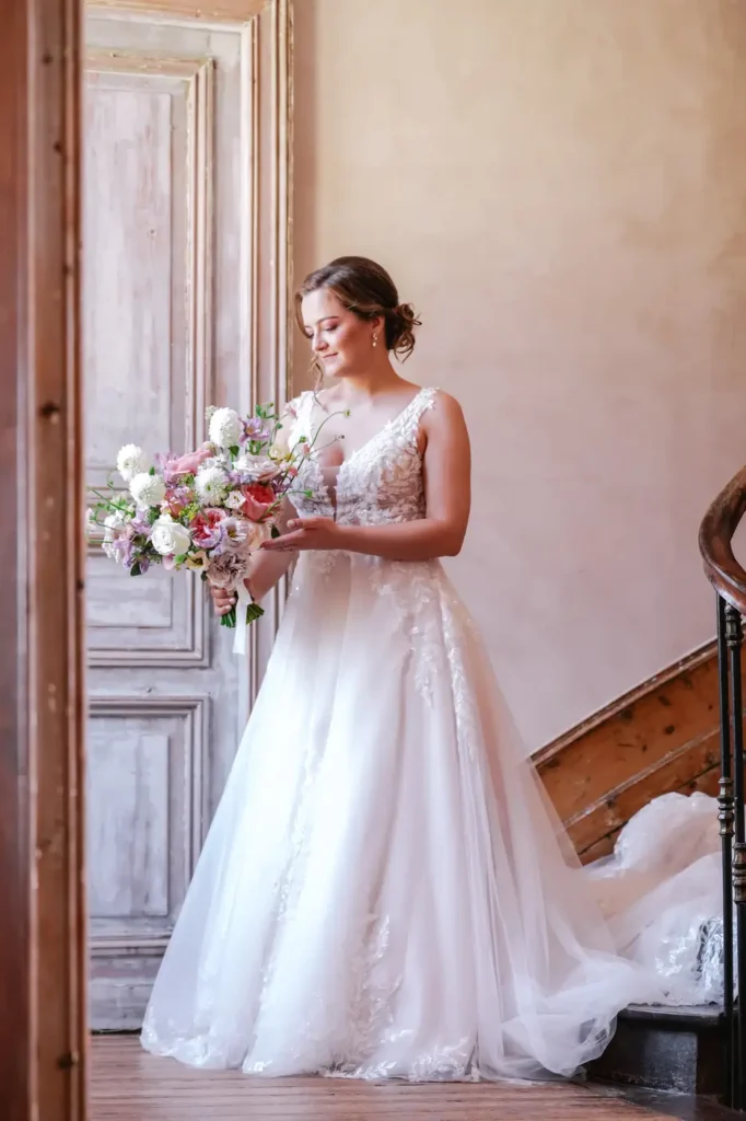 La mariée tenant son bouquet dans une chambre du château