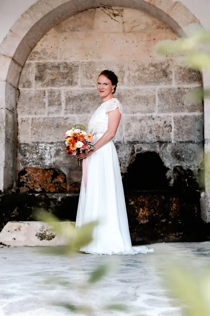 Mariée posant près d’un mur en pierre en Dordogne