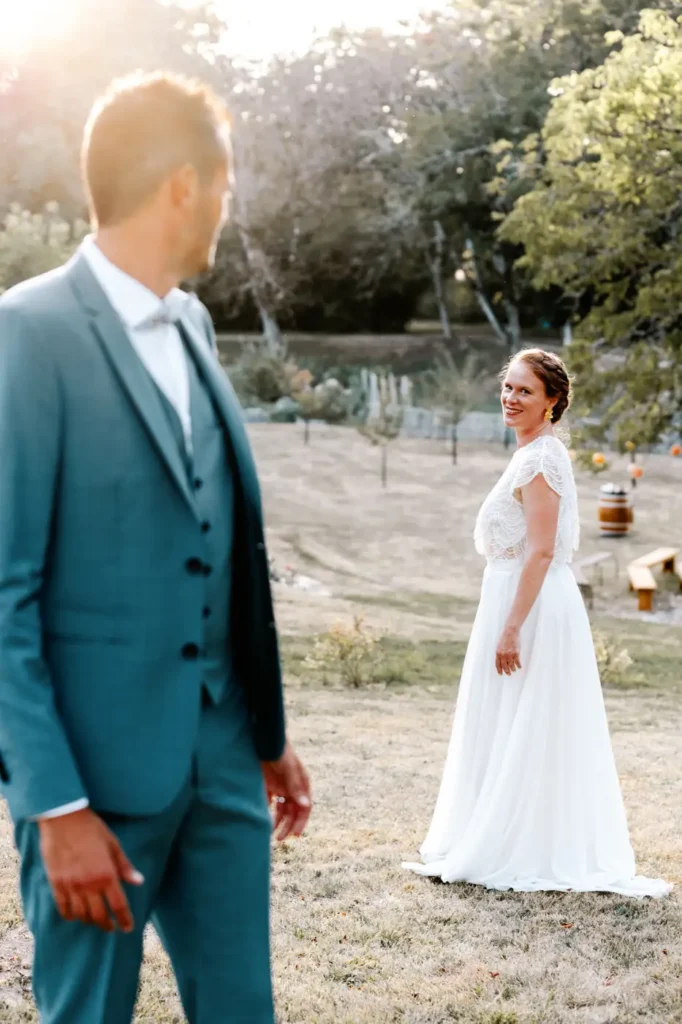 Mariée en arrière-plan et marié au premier plan se retournant vers elle au Domaine de la Vallade