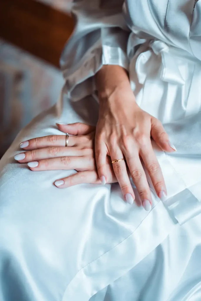 Les mains de la mariée posées sur sa robe en satin